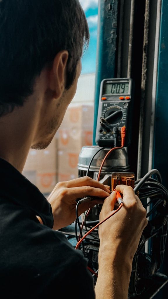 Electrician using a multimeter to check voltages in an industrial setting.