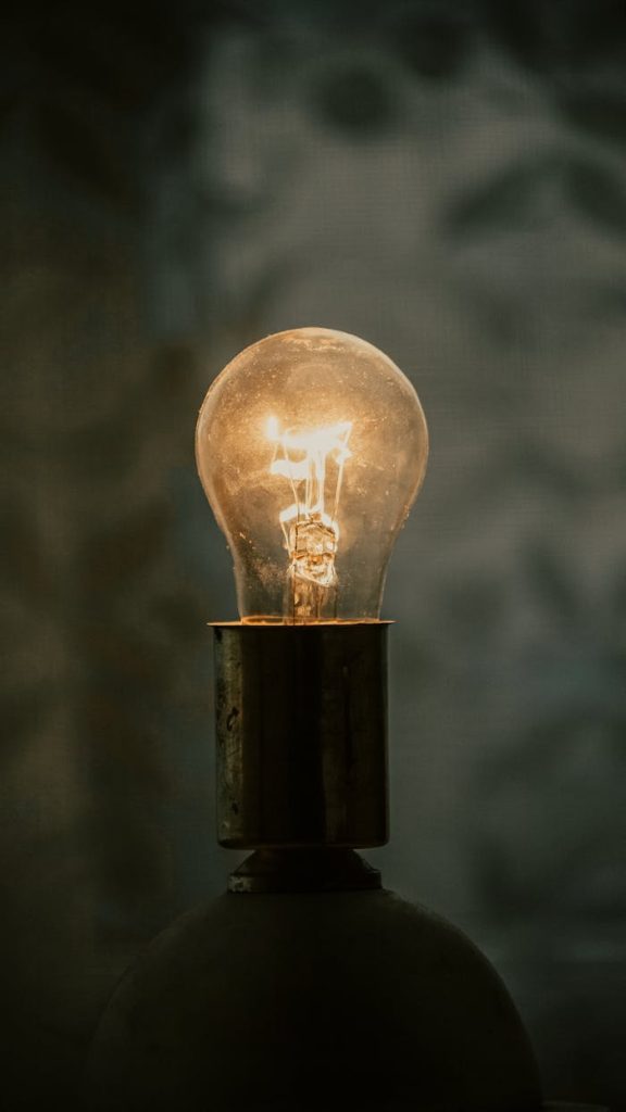 A close-up of a glowing light bulb with a warm ambiance against a blurred background.